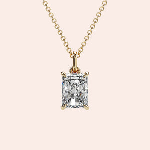 A close-up of a radiant-cut solitaire diamond pendant in a four-prong yellow gold setting. The structured shape of the radiant cut enhances the diamond's brilliance and fire.
