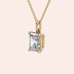 A detailed side view of a radiant-cut diamond solitaire pendant in a four-prong yellow gold basket setting. The intricate craftsmanship ensures the perfect balance of security and elegance.
