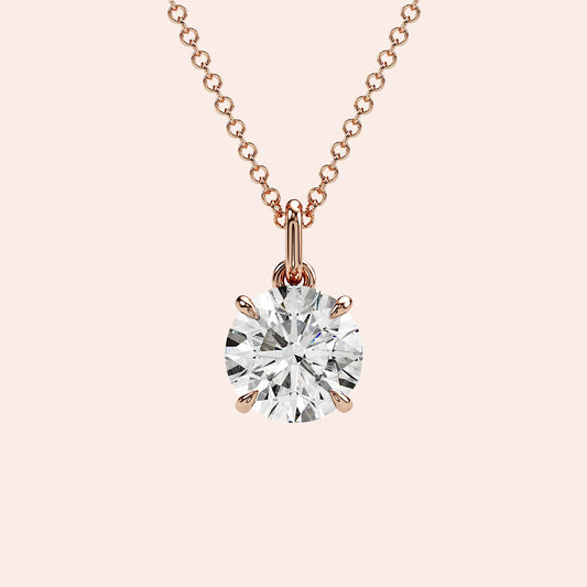A close-up of a solitaire round-cut diamond pendant in a four-prong rose gold setting. The brilliance of the round diamond is enhanced by the delicate yet secure setting.
