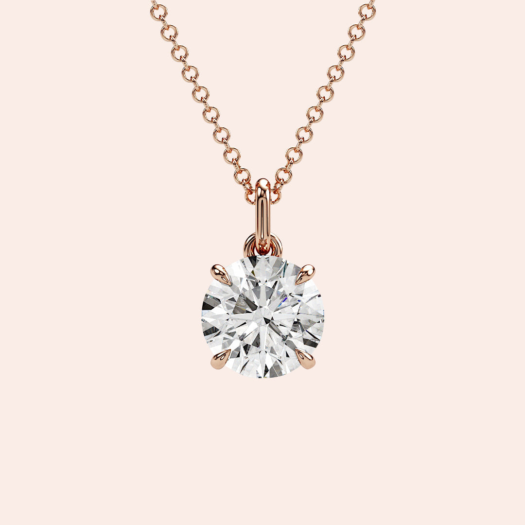 A close-up of a solitaire round-cut diamond pendant in a four-prong rose gold setting. The brilliance of the round diamond is enhanced by the delicate yet secure setting.
