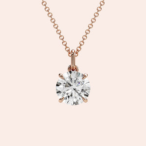 A close-up of a solitaire round-cut diamond pendant in a four-prong rose gold setting. The brilliance of the round diamond is enhanced by the delicate yet secure setting.

