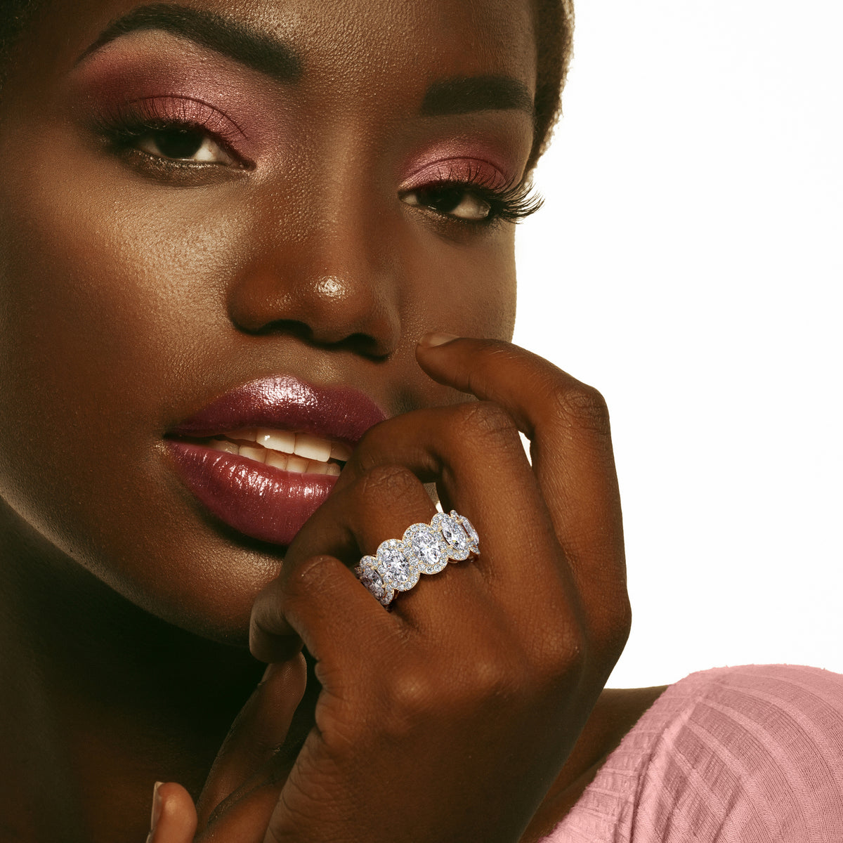 Elegant 14K gold oval eternity wedding band worn on model's hand, featuring a row of diamonds in a unique design. 