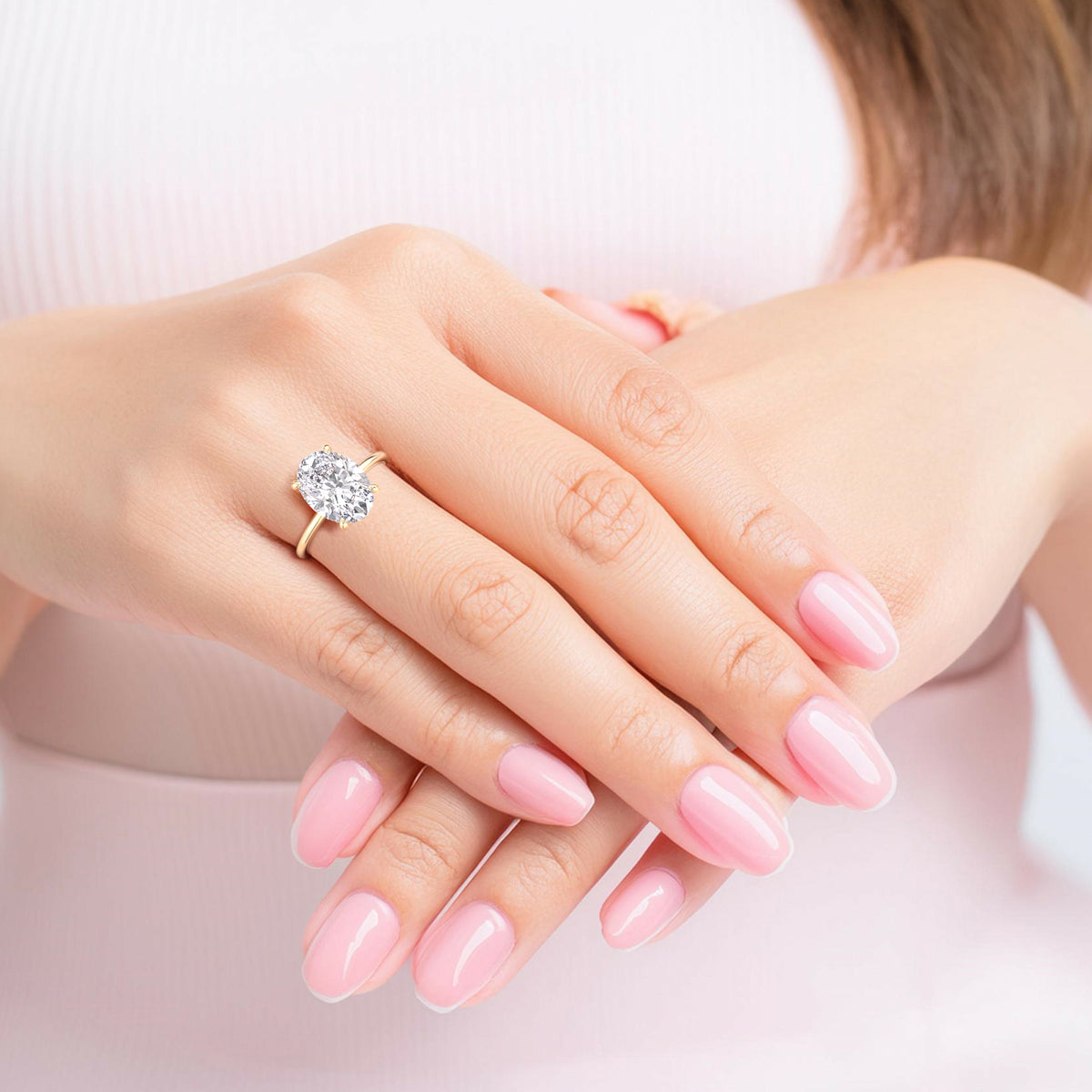 Oval diamond engagement ring in 14K or 18K gold, worn on a model’s finger, radiating timeless elegance and lustrous shine.