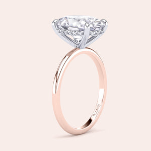 Two-tone 14K/18K white and rose gold engagement ring featuring an oval cut diamond in a secret halo solitaire design. 