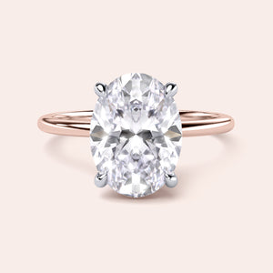 Two-tone oval diamond ring in 14K/18K white and rose gold, featuring a secret halo solitaire design. Perfect for engagements. 