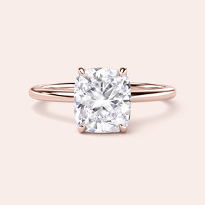 A stunning cushion-cut diamond engagement ring in 14K or 18K rose gold, featuring a delicate band and prominent centerpiece. 