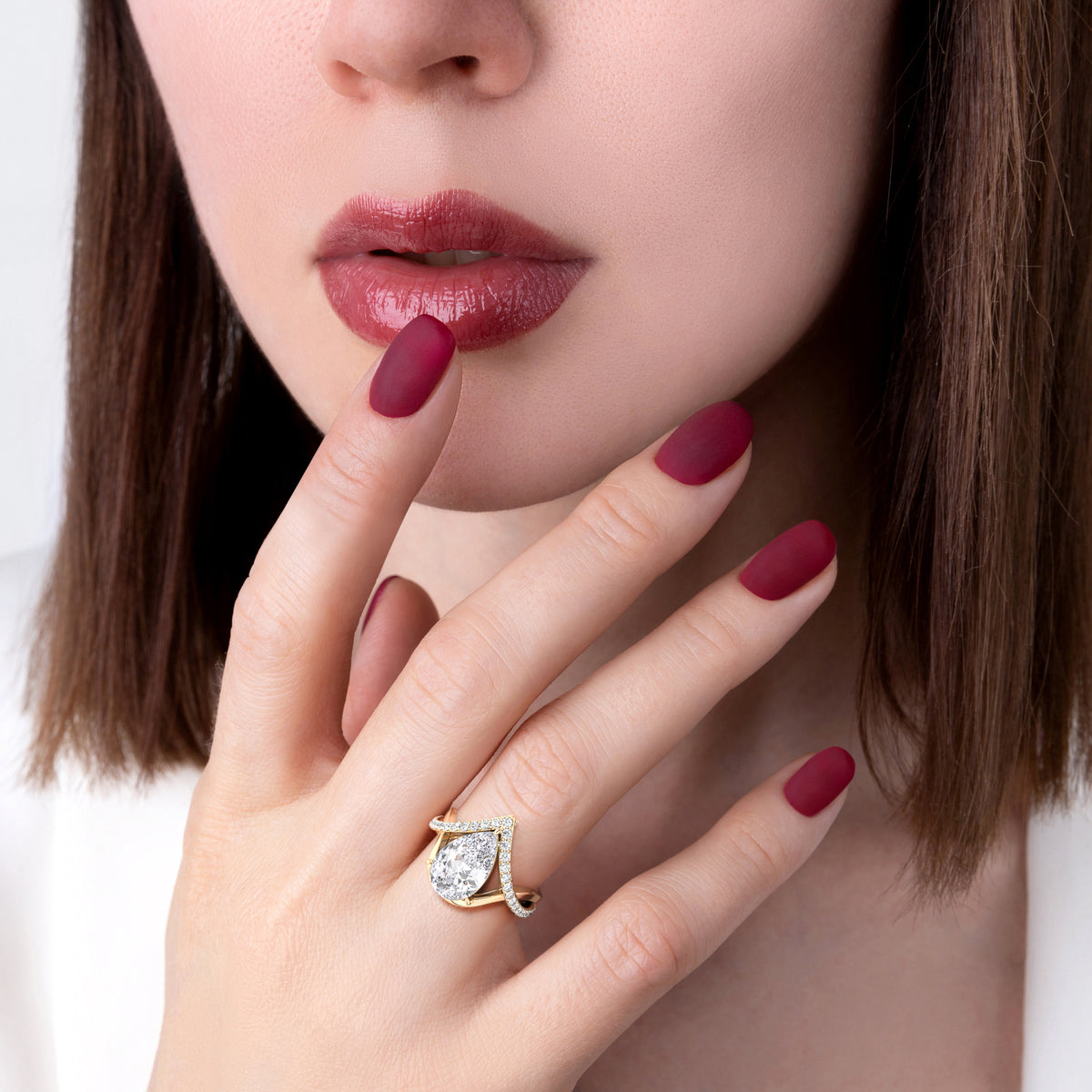 Pear-shaped diamond ring in 14K, 18K gold, or platinum, showcasing an elegant design with a shimmering centerpiece on a model's hand.