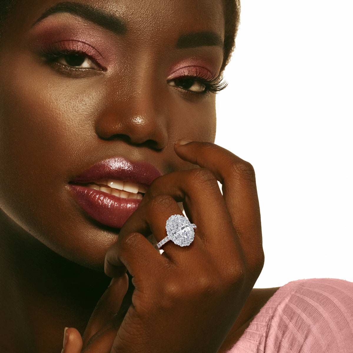 Two-tone 14K gold diamond ring featuring an oval shape, halo design, and pave band, worn on a model's hand. 