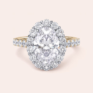 Two-tone 14K white and yellow gold engagement ring featuring an oval diamond, halo, and pave diamond band, unworn. 