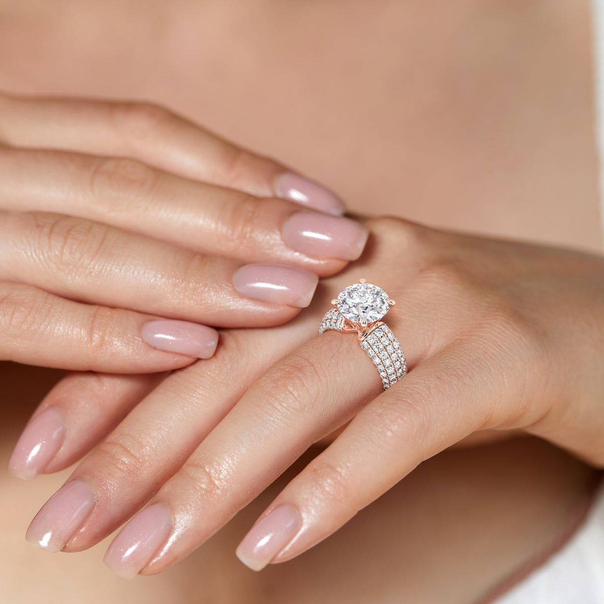 Stunning 14K gold round cut diamond engagement ring on a model's finger, featuring encrusted bands of smaller diamonds.