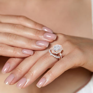 Hands elegantly displaying vintage-inspired oval halo diamond ring set featuring delicate filigree details in recycled rose gold 