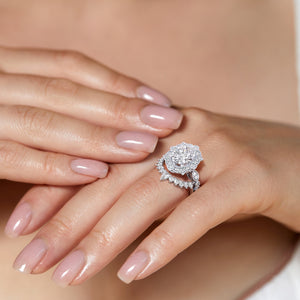 Hands elegantly displaying vintage-inspired oval halo diamond ring set featuring delicate filigree details in recycled white gold 