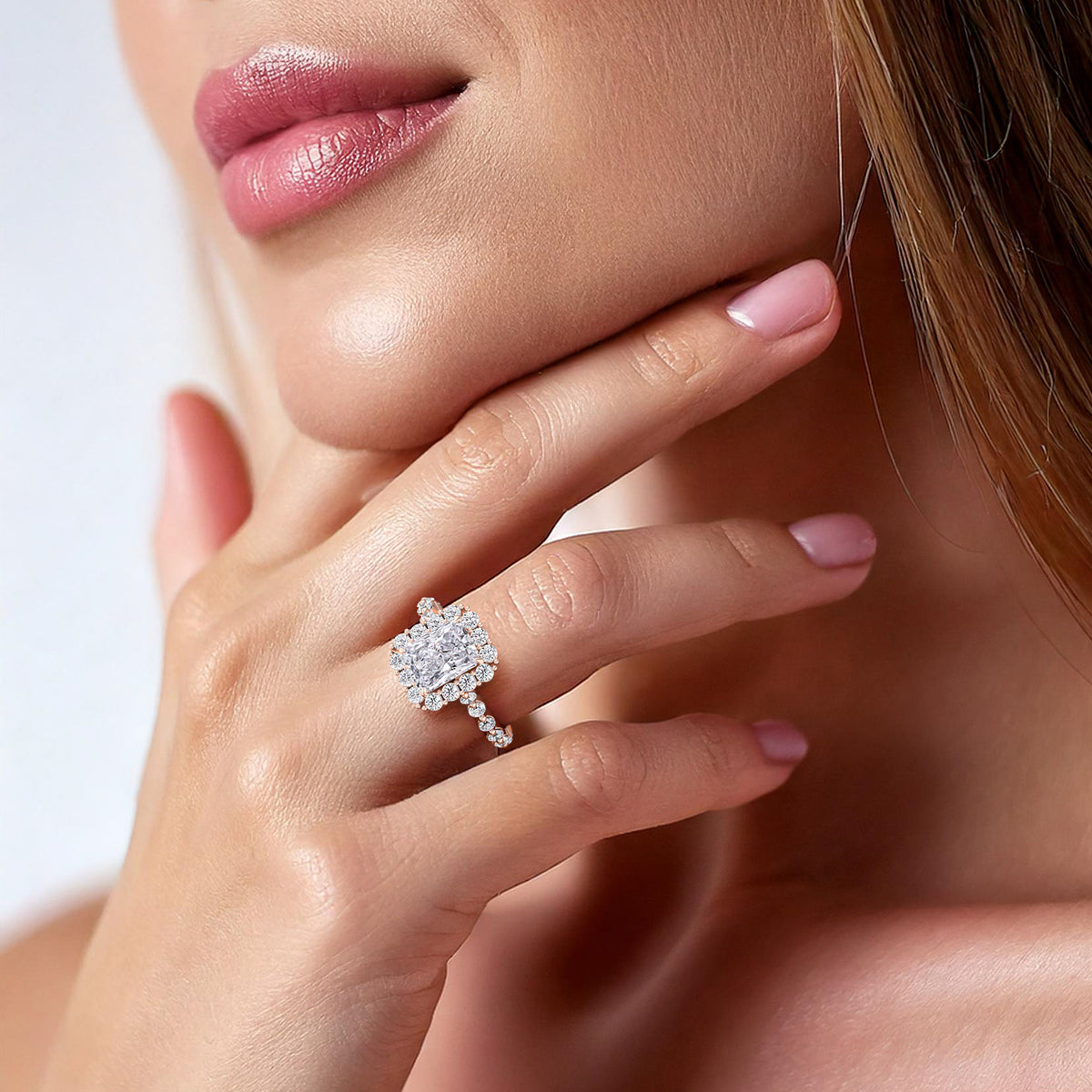 Beautifully styled woman wearing radiant-cut diamond engagement ring, accented with a sparkling halo and diamond band in rose gold 
