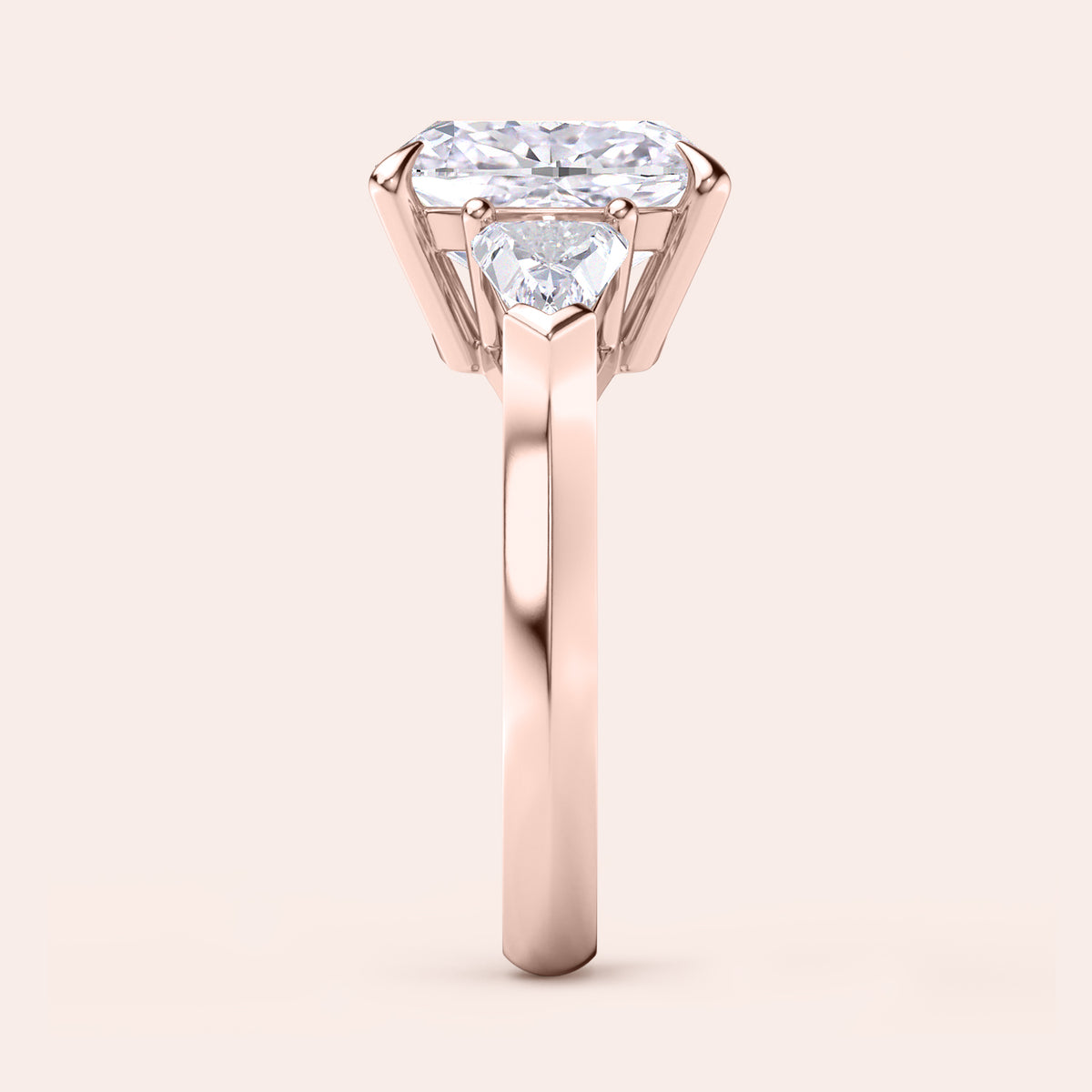 Side view of cushion-cut diamond three stone engagement ring with dazzling shield side stones in rose gold 