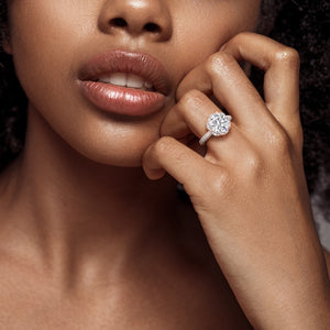 Chic woman showcasing a rose gold engagement ring with a cushion-cut center diamond and an intricate double halo, captured in a moment of refined beauty. 