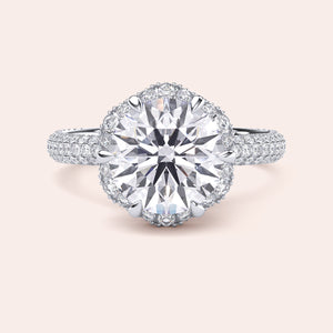 Front view of a luxurious cushion-cut diamond engagement ring in white gold, adorned with a double halo of diamonds and a sparkling pavé band. 