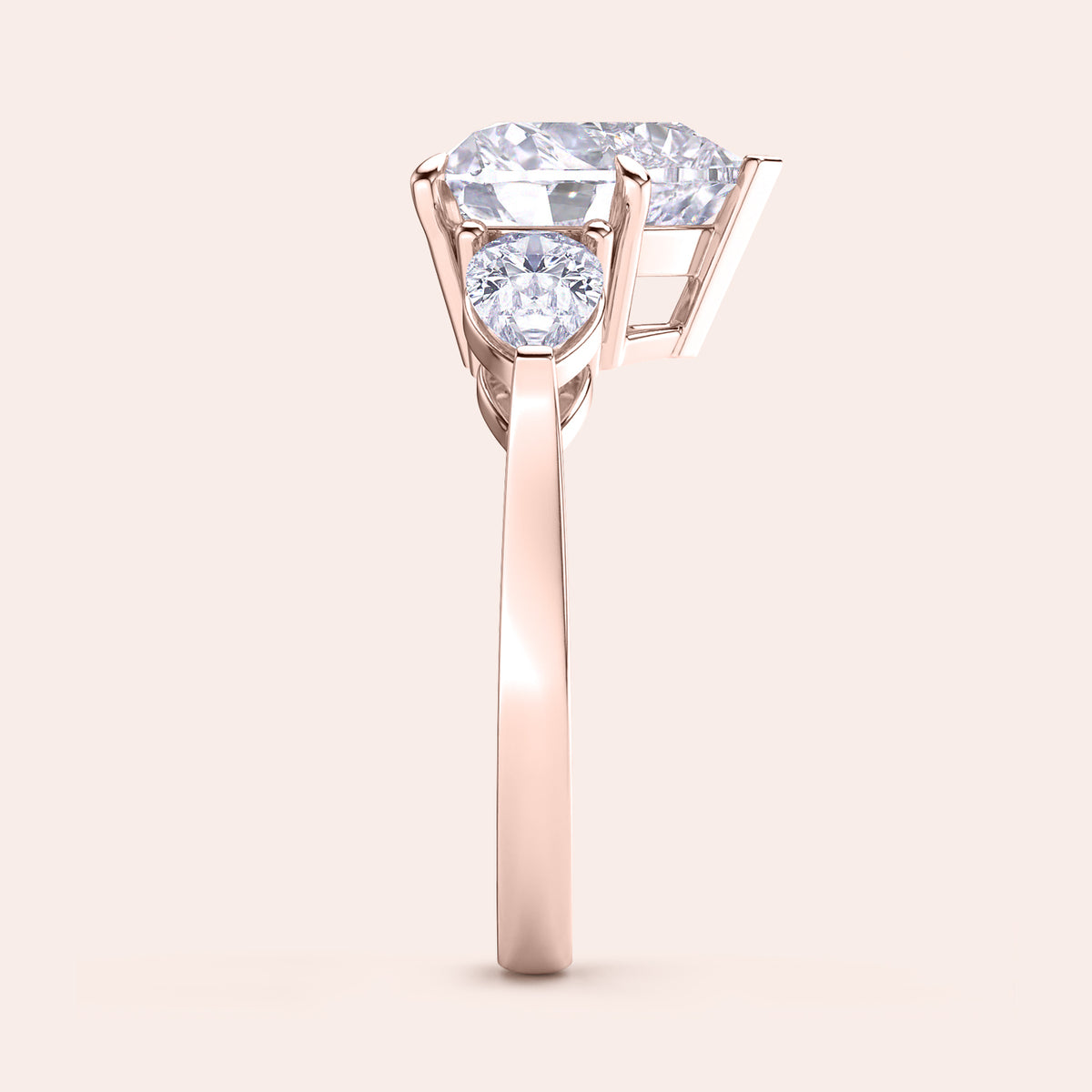 Side view of a rose gold heart-shaped diamond engagement ring, showcasing its prong settings and shimmering teardrop side stones. 