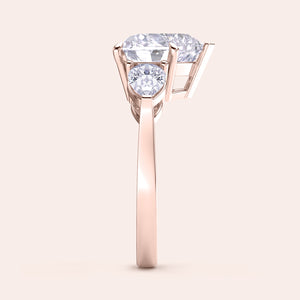 Side view of a rose gold heart-shaped diamond engagement ring, showcasing its prong settings and shimmering teardrop side stones. 