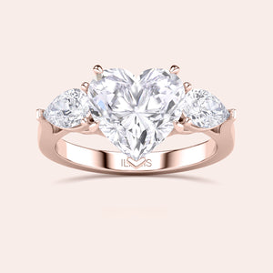 Close-up of a rose gold engagement ring with a heart-shaped diamond center and teardrop diamond accents along the band, reflecting sophisticated craftsmanship. 