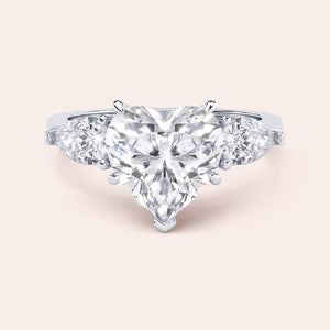 Close-up of a white gold engagement ring with a heart-shaped diamond center and teardrop diamond accents along the band, reflecting sophisticated craftsmanship. 