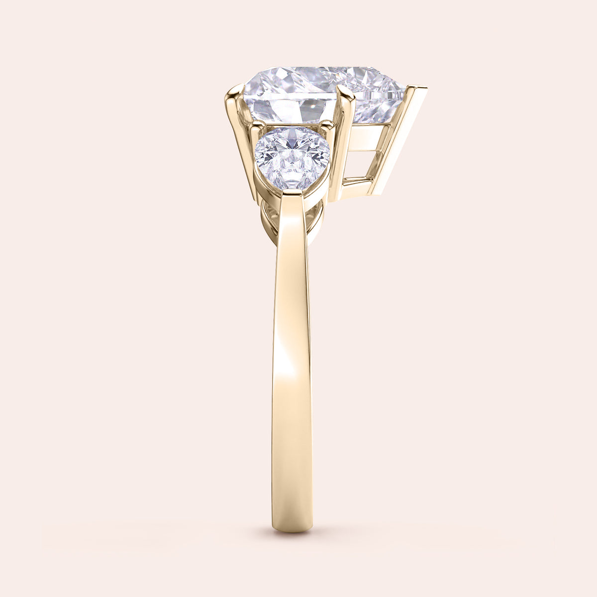 Side view of a yellow gold heart-shaped diamond engagement ring, showcasing its prong settings and shimmering teardrop side stones. 