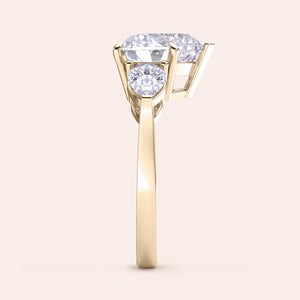 Side view of a yellow gold heart-shaped diamond engagement ring, showcasing its prong settings and shimmering teardrop side stones. 