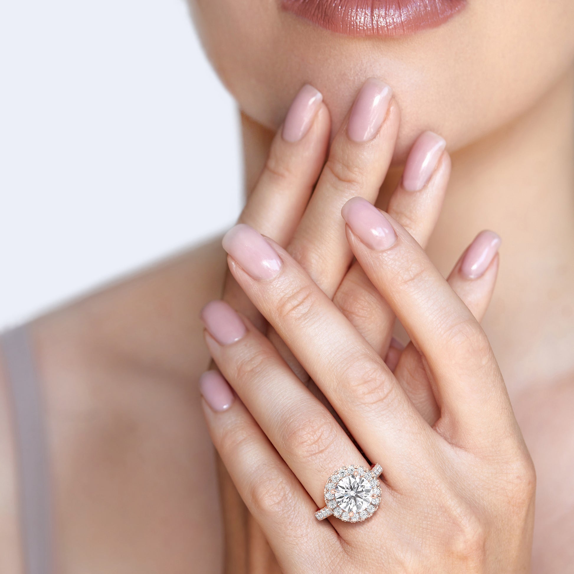 Woman wearing a rose gold engagement ring with a round-cut diamond halo, highlighting the ring’s romantic allure and classic design. | #14KRecycledRoseGold #18KRecycledRoseGold