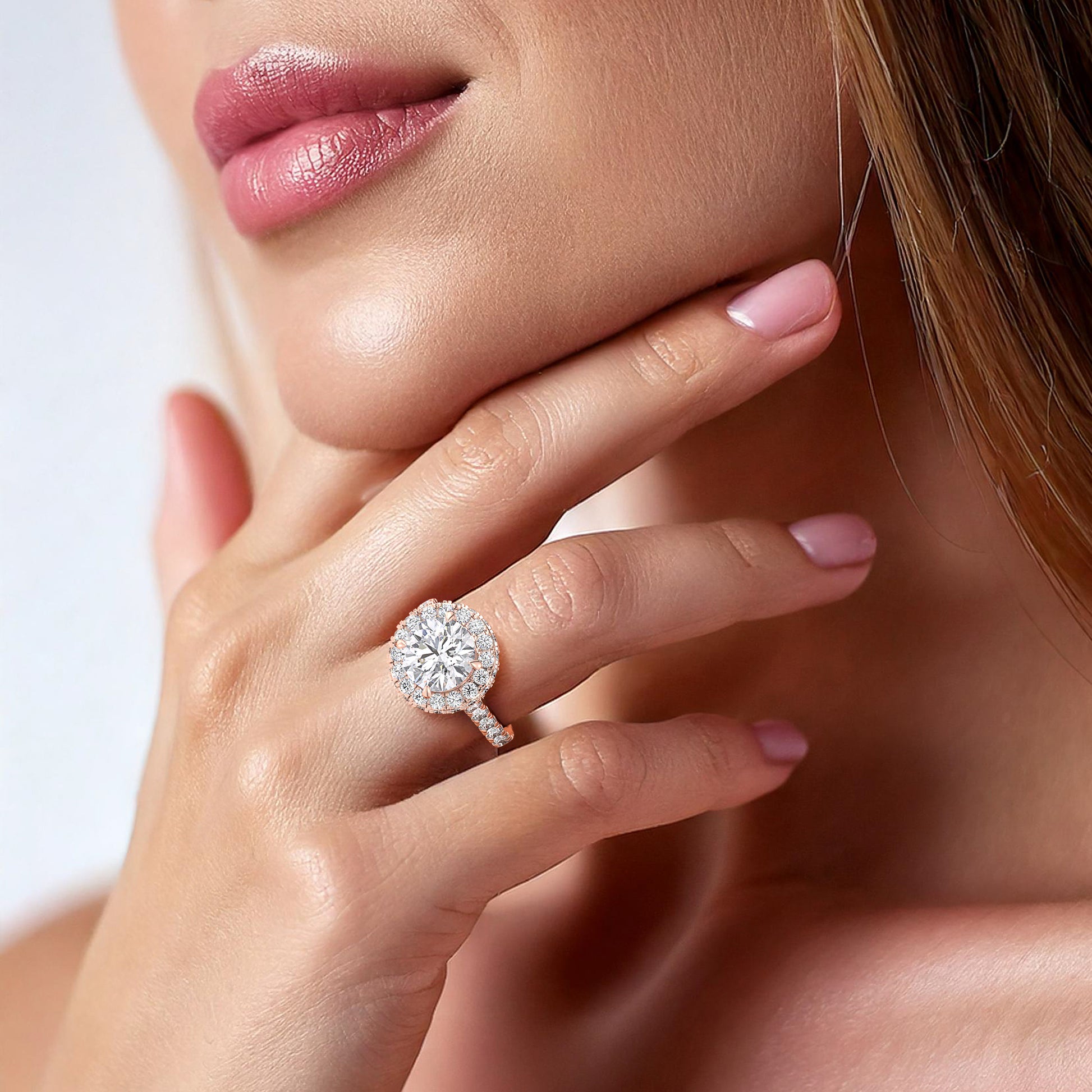 ophisticated rose gold engagement ring with a round-cut diamond and halo setting, showcased on a woman’s finger, symbolizing eternal love. | #14KRecycledRoseGold #18KRecycledRoseGold