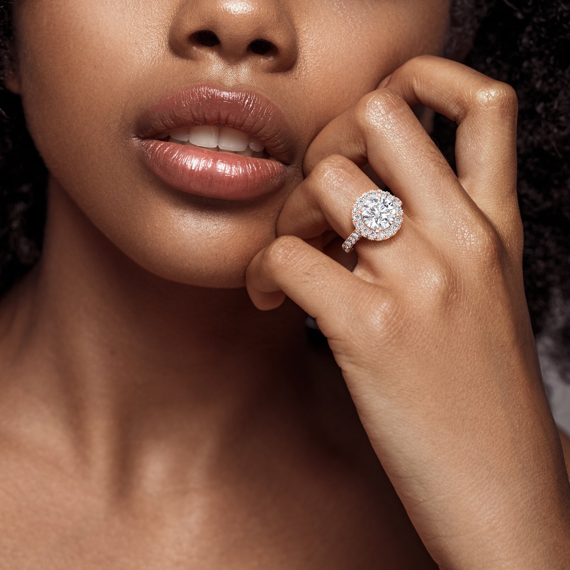 Chic and stylish, a rose gold round-cut diamond engagement ring worn by a woman, its halo setting enhancing the overall elegance and glamour. | #14KRecycledRoseGold #18KRecycledRoseGold