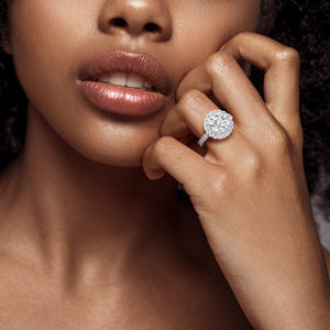 Chic and stylish, a white gold round-cut diamond engagement ring worn by a woman, its halo setting enhancing the overall elegance and glamour. 