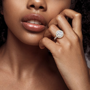 Sophisticated yellow gold engagement ring with a round-cut diamond and halo setting, showcased on a woman’s finger, symbolizing eternal love. 