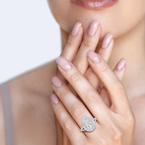 Close-up of a white gold engagement ring worn on hand, featuring a radiant heart-shaped diamond encircled by a double halo of diamonds, embodying pure romance and sophistication. #14KRecycledWhiteGold #18KRecycledWhiteGold #Platinum