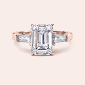 Rose gold engagement ring featuring an elongated emerald-cut diamond, set in a sleek, modern band, with ILANIS engraved inside. 