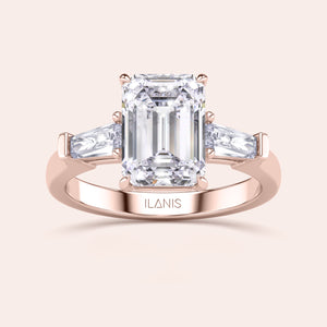 Rose gold engagement ring featuring a prominent emerald-cut diamond, flanked by smaller diamonds on a delicate band, exuding luxury. 