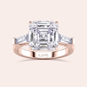 Stunning rose gold ring with a central emerald-cut diamond flanked by trapezoid diamonds set in a classic design 