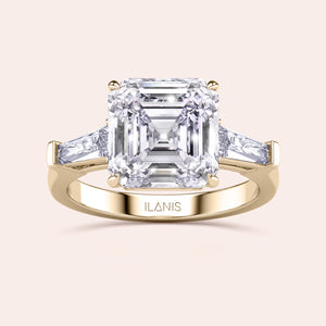 Stunning yellow gold ring with a central emerald-cut diamond flanked by trapezoid diamonds set in a classic design 