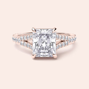 14K rose gold engagement ring with radiant cut diamond center, side diamonds, intricate design, displayed in close-up view.