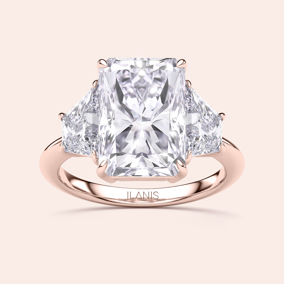Elegant 14K or 18K rose gold three-stone engagement ring with a radiant-cut diamond and triangular side stones.