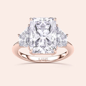 Elegant 14K or 18K rose gold three-stone engagement ring with a radiant-cut diamond and triangular side stones.