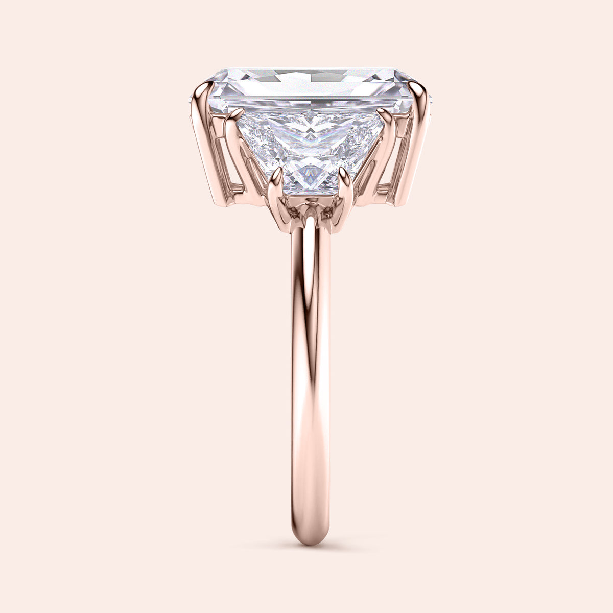 "Elegant 14K rose gold engagement ring with a stunning three-stone trapezoid design, showcasing radiant diamonds in exquisite prong settings."