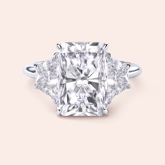 "Radiant cut three-stone engagement ring in 14K/18K gold or platinum, featuring a center diamond and trapezoid side stones."
