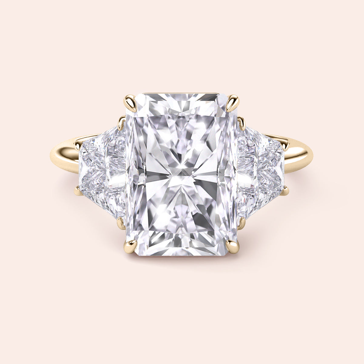 Radiant-cut diamond engagement ring with side stones in 14K gold, showcased against a neutral background.
