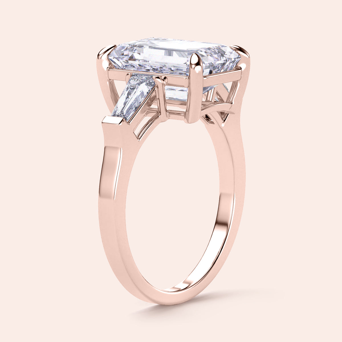 Elegant rose gold engagement ring featuring an emerald-cut diamond and tapered baguette side stones in 14K or 18K gold.