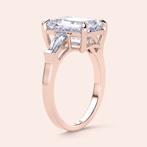Elegant rose gold engagement ring featuring an emerald-cut diamond and tapered baguette side stones in 14K or 18K gold.