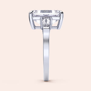 Side view of a radiant-cut emerald engagement ring in 14K white gold, featuring three tapered baguettes and exquisite craftsmanship.