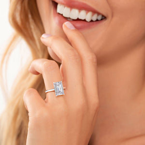 Close-up of a model wearing an elegant 14K white gold emerald solitaire cathedral ring, showcasing refined beauty and sparkle.