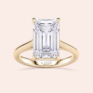 "Elegant 14K yellow gold engagement ring featuring a stunning emerald-cut diamond in a classic cathedral setting by Ilanis."