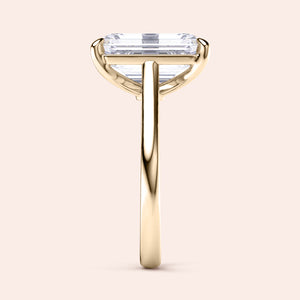 Elegant 14K or 18K gold engagement ring featuring an emerald-cut diamond, showcased in profile view on a neutral background.