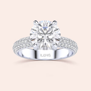 Elegant 14K/18K white gold engagement ring with a round diamond center and pave diamond band on a beige background.