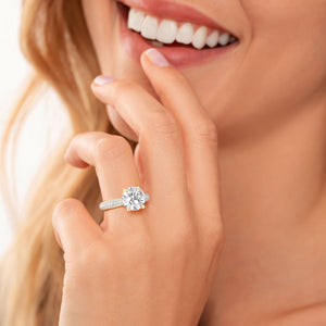 Close-up of a woman's hand wearing a stunning 14K yellow gold round pave solitaire engagement ring with sparkling diamonds.